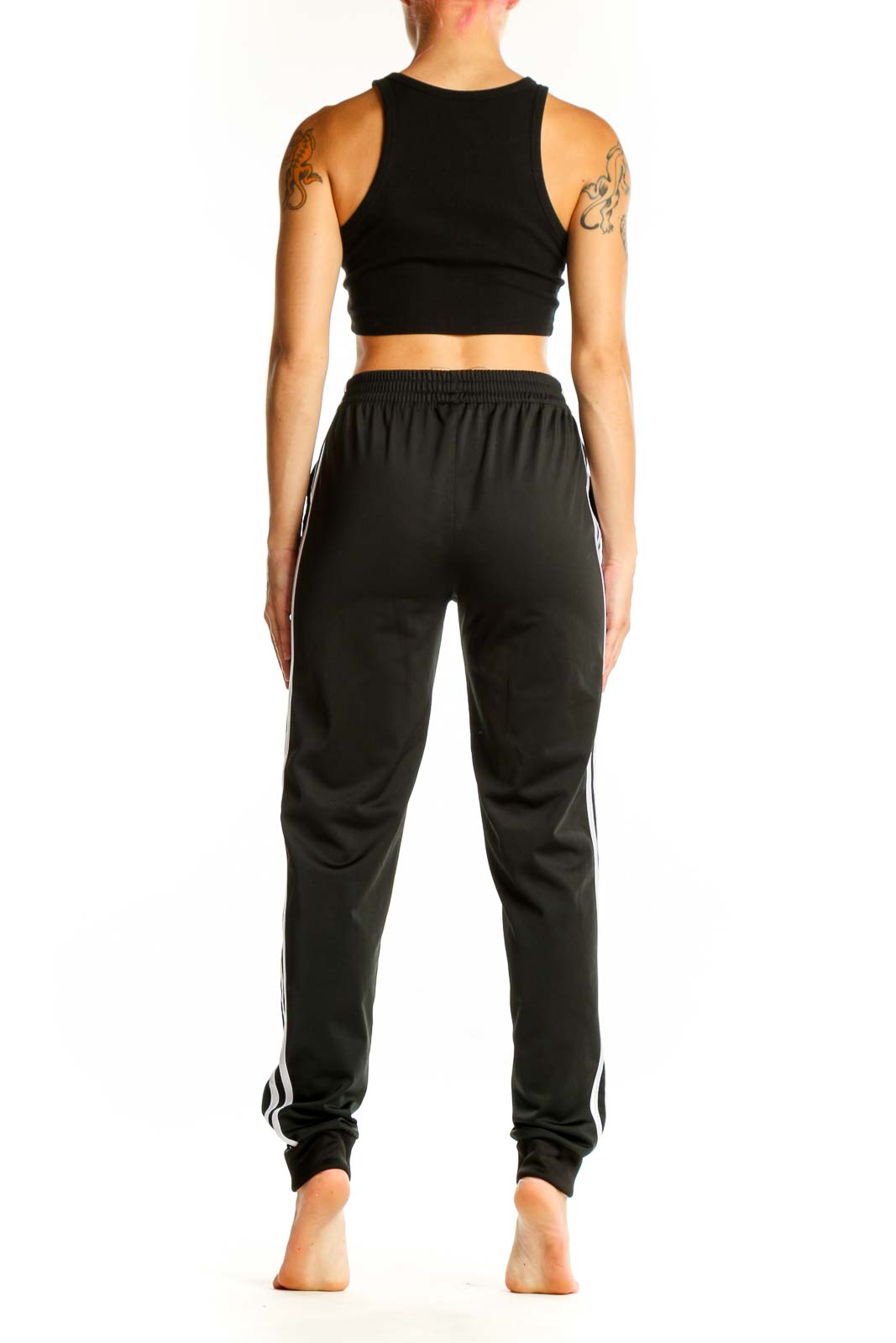 Side view of woman wearing black Adidas track pants with white stripes