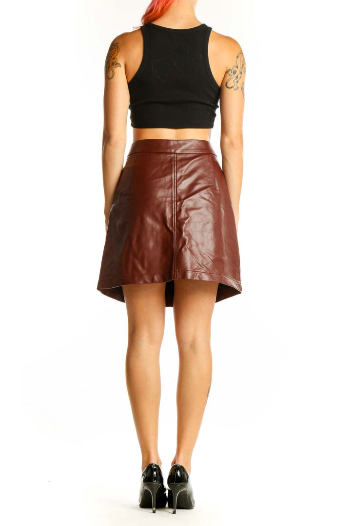 Side view of model wearing French Connection brown faux leather mini skirt with black crop top