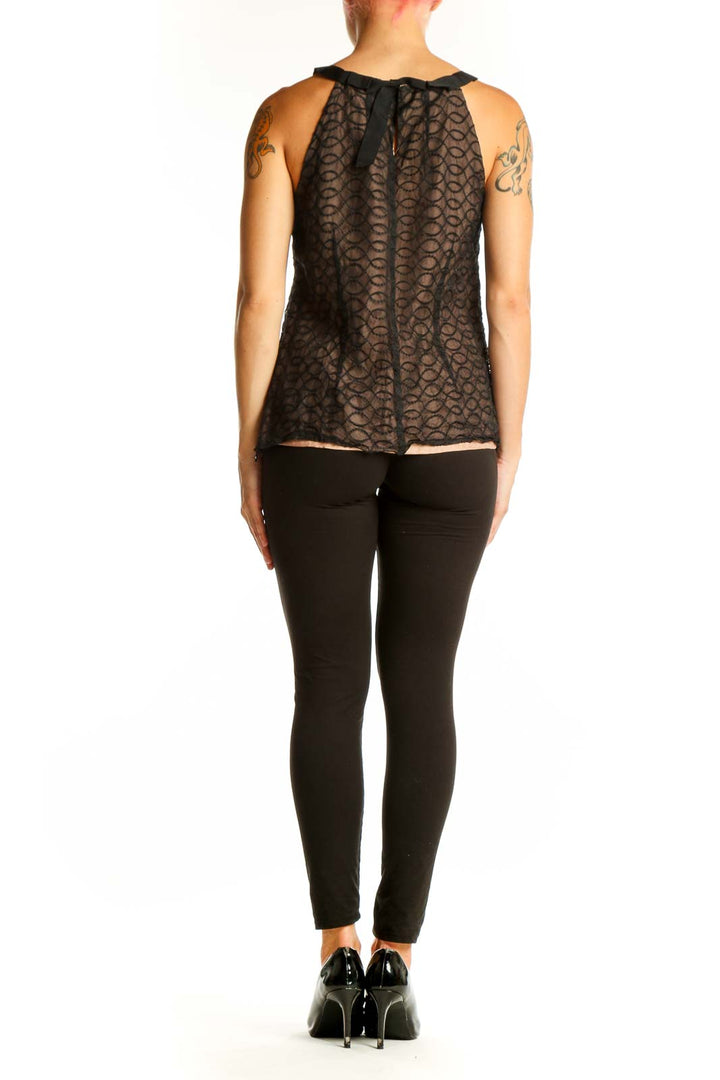 Side view of model wearing Kenar Black Lace Overlay Sleeveless Top with black pants