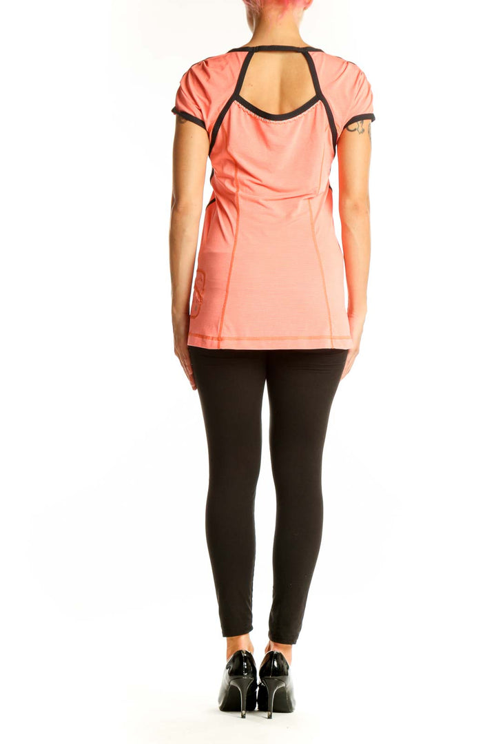 Side view of coral Lululemon V-neck performance top showing black side panels
