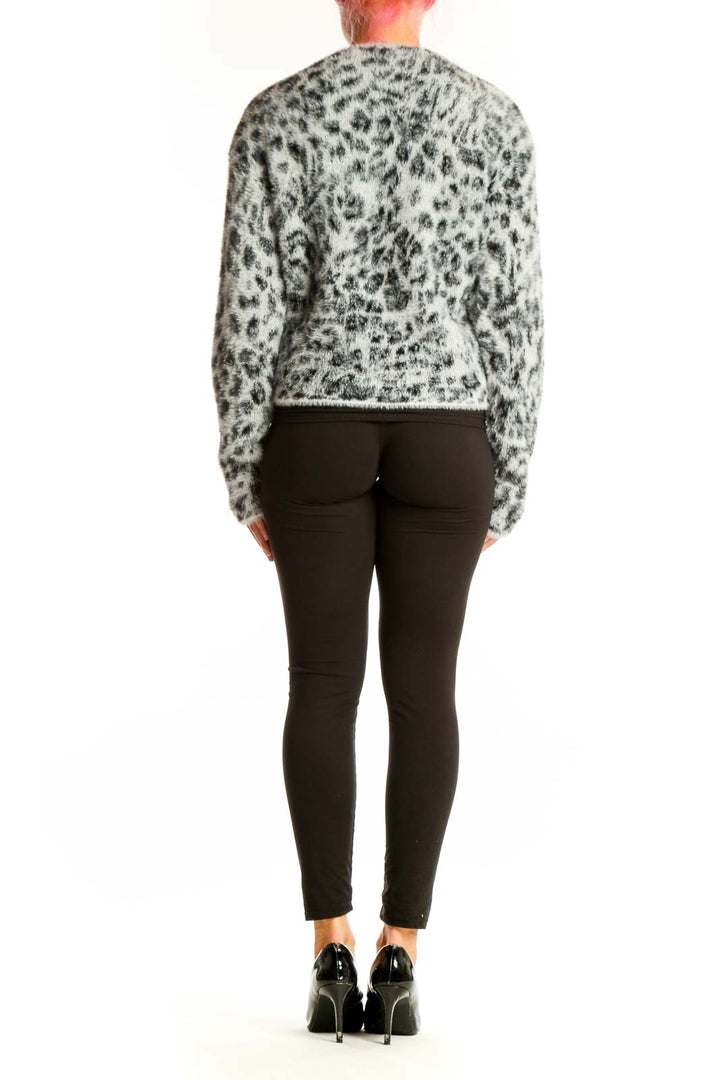 Side view of model wearing gray leopard print fuzzy knit sweater with black pants