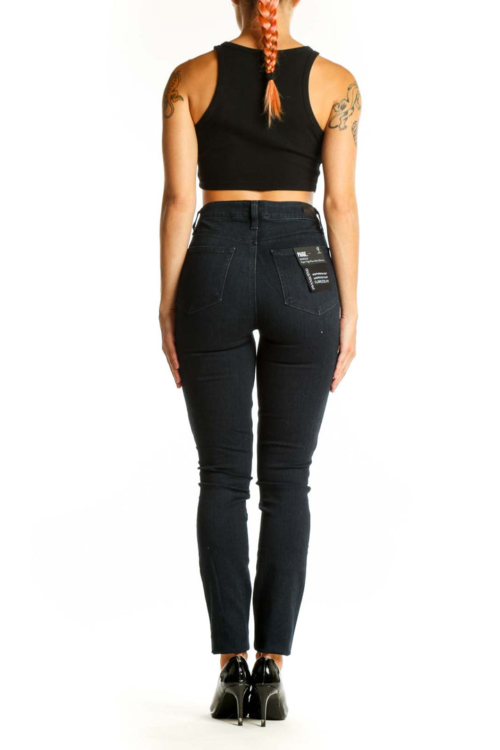 Side view of Paige dark blue high-waisted skinny jeans on model with black crop top