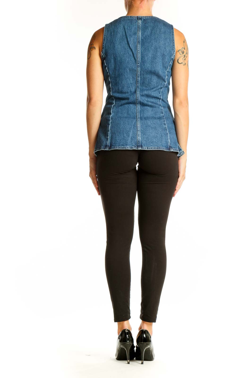 Side view of woman wearing Madewell blue denim vest with black pants