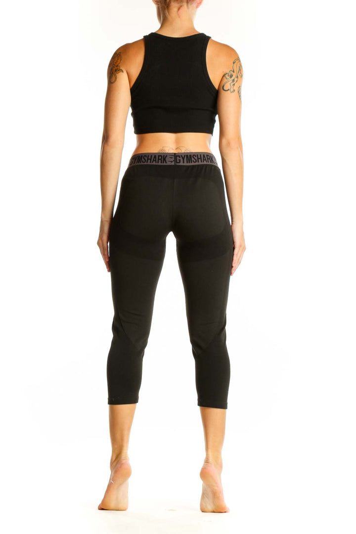 Side view of woman wearing black Gymshark capri leggings and crop top