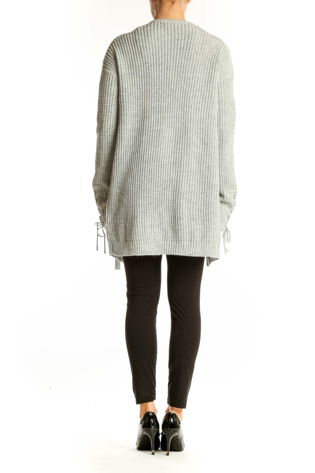 Side view of model wearing gray chunky knit cardigan over black outfit