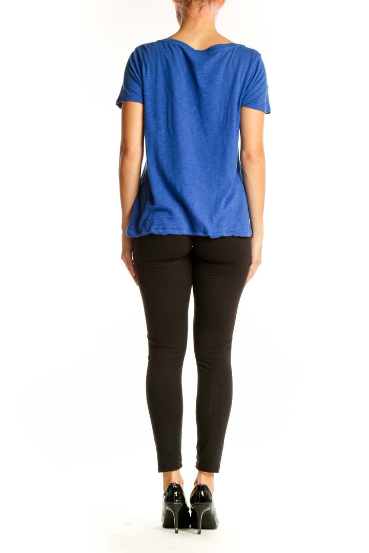 Side view of woman wearing blue J.Crew V-neck short sleeve cotton top with black pants