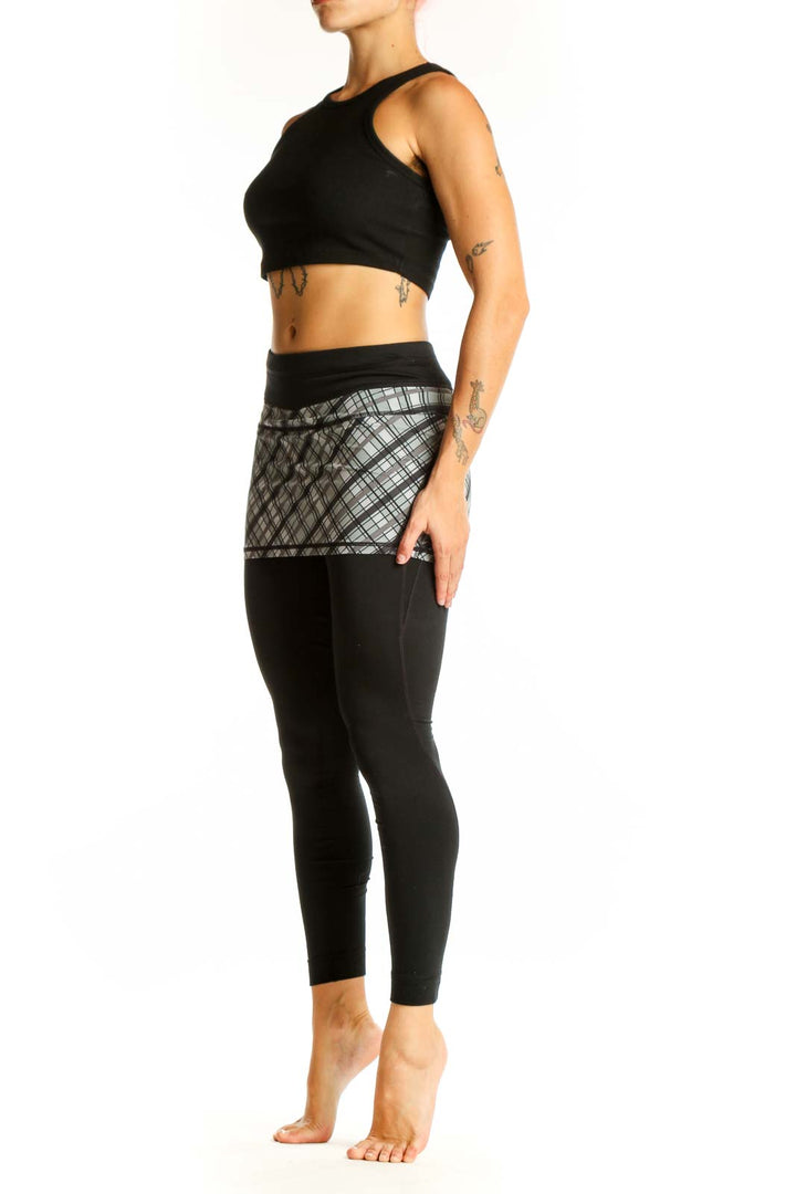 Front view of Athleta black leggings with gray plaid skirt overlay