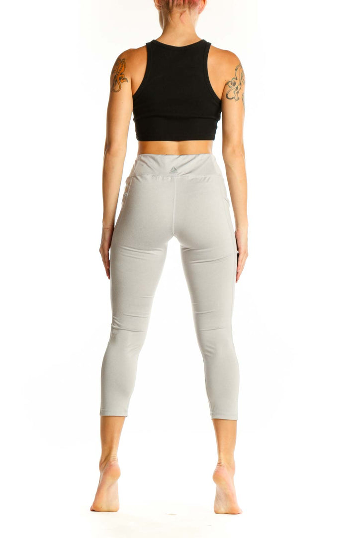 Side view of woman wearing light gray Reebok capri leggings with black crop top