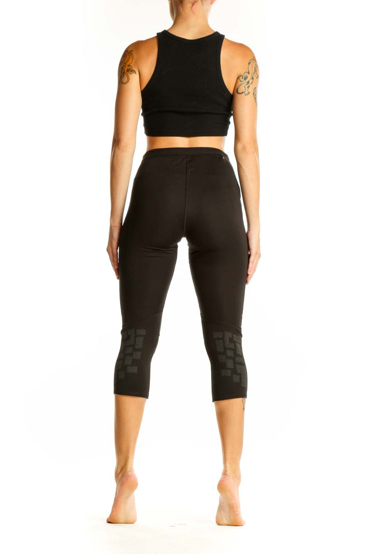 Side view of woman wearing black Adidas capri leggings and matching crop top