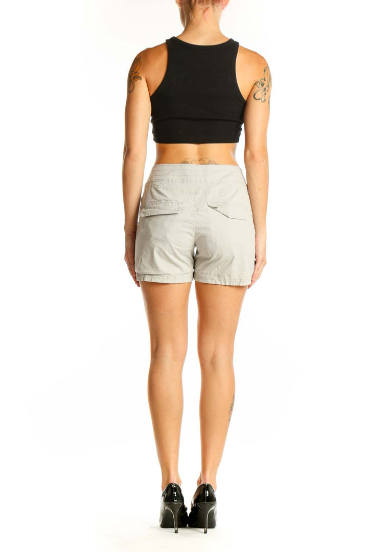 Side view of woman wearing Nau beige shorts with black top