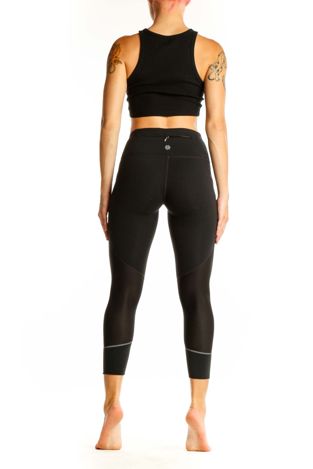 Side view of woman wearing black Nike high-waisted cropped leggings and matching crop top