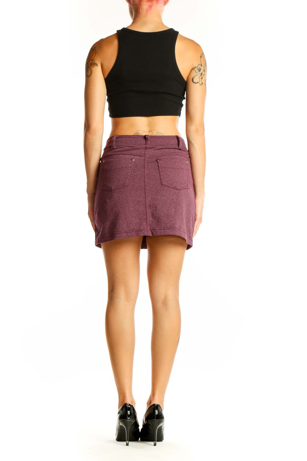 Side view of woman wearing Athleta burgundy mini skirt with black top