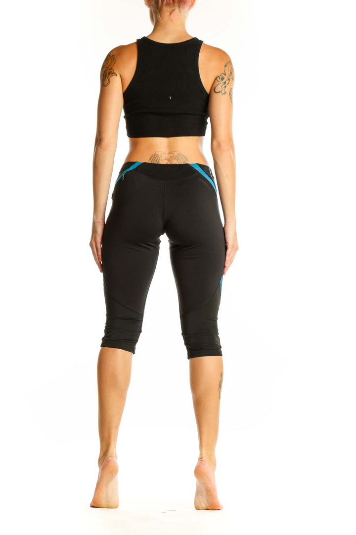 Side view of woman wearing black Adidas capri leggings with blue accents