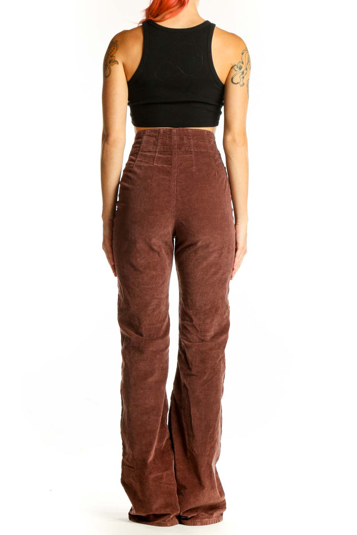 Back view of WE THE FREE brown corduroy high-waisted flared pants on model with black crop top