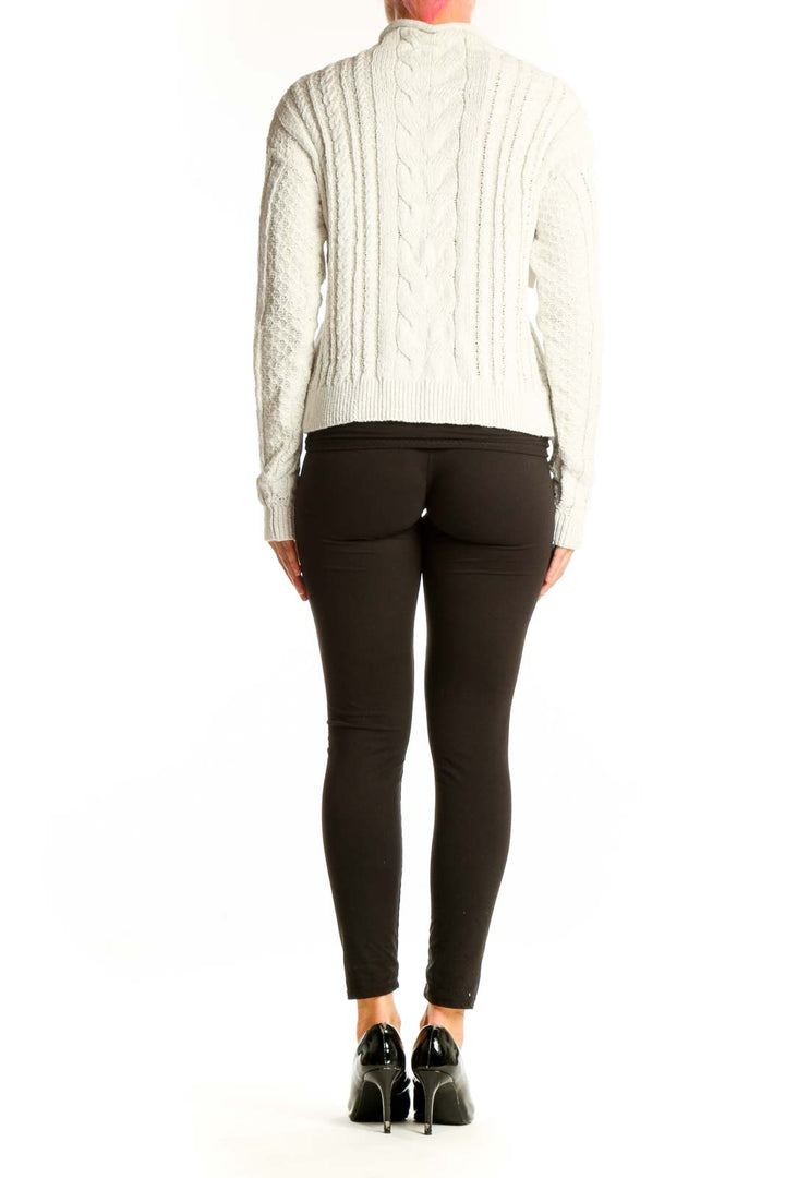 Side view of model wearing cream J.Crew cable knit mock neck sweater with black pants