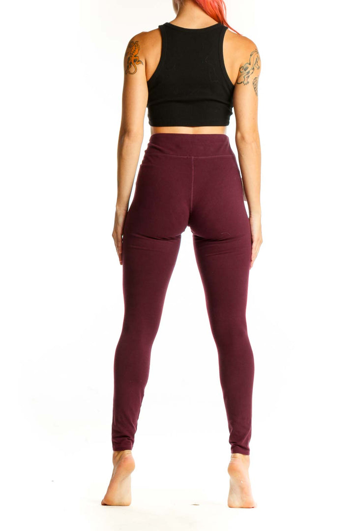 Side view of burgundy Pact leggings with black crop top on model