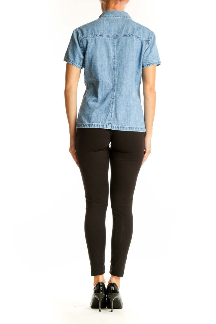 Side view of woman wearing Gap light blue denim short-sleeve button-up shirt with black pants