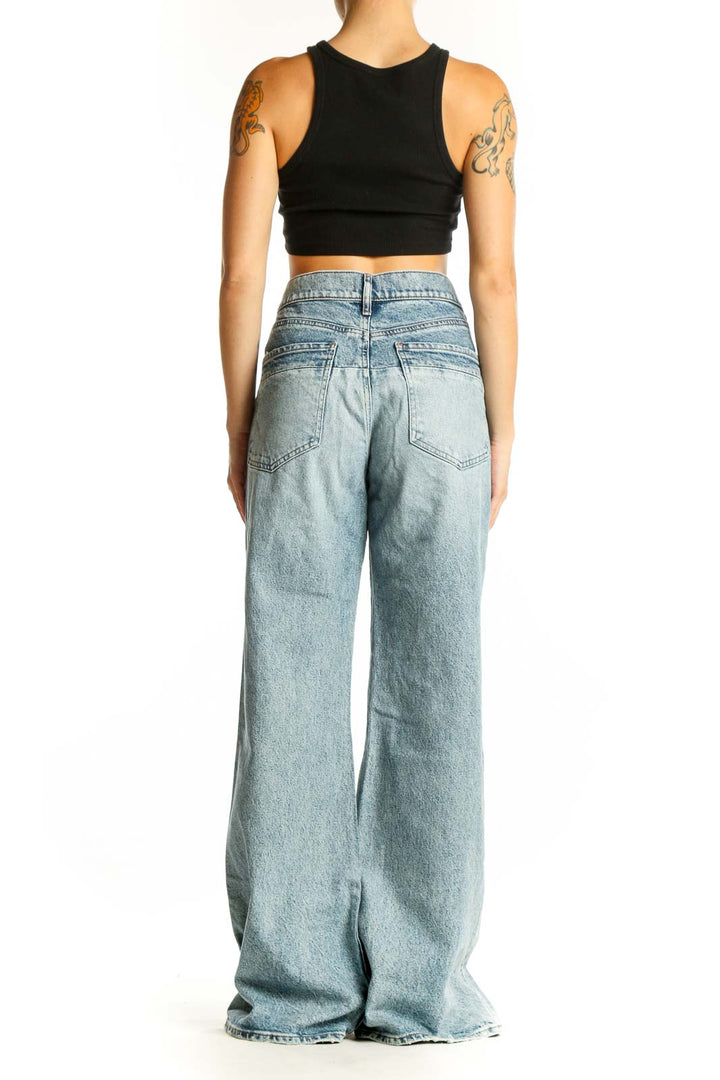 Side view of Gap light blue distressed wide-leg jeans on model with black crop top