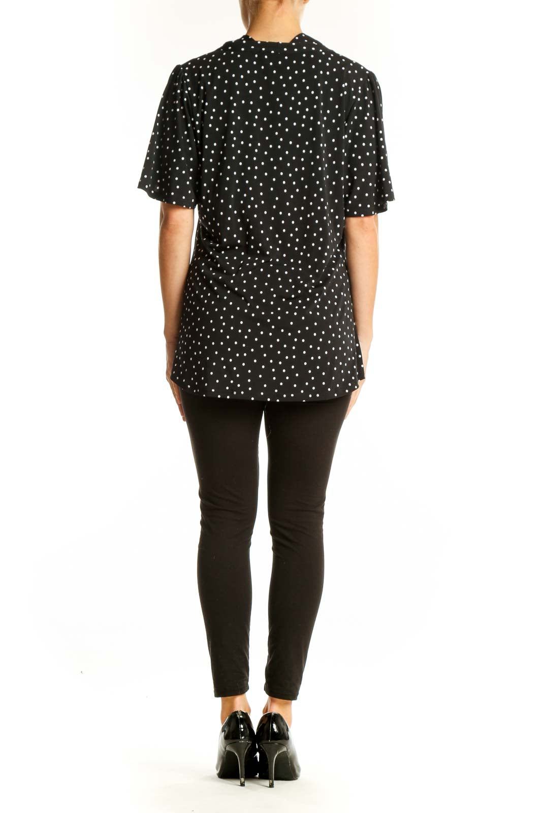 Side view of model wearing Beacon black polka dot blouse with black pants