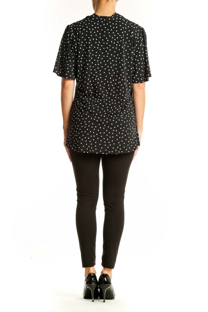 Side view of model wearing Beacon black polka dot blouse with black pants