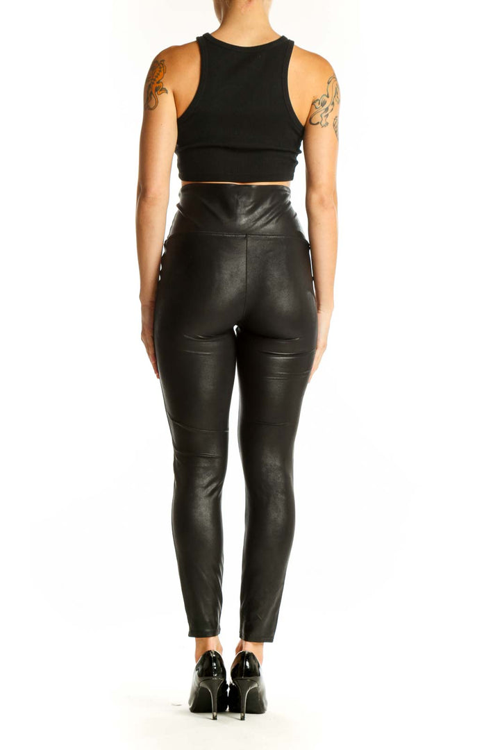 Side view of woman wearing Spanx black high-waisted faux leather leggings with white stripe