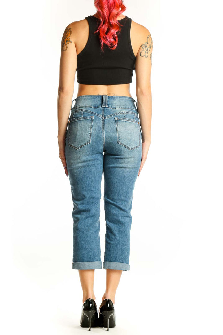 Blue denim cropped jeans with rolled cuffs, back view showing classic five-pocket design