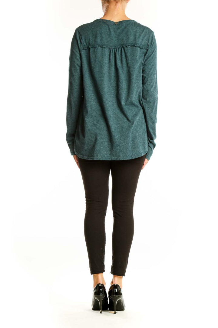 Side view of model wearing teal prAna V-neck long sleeve top with black pants