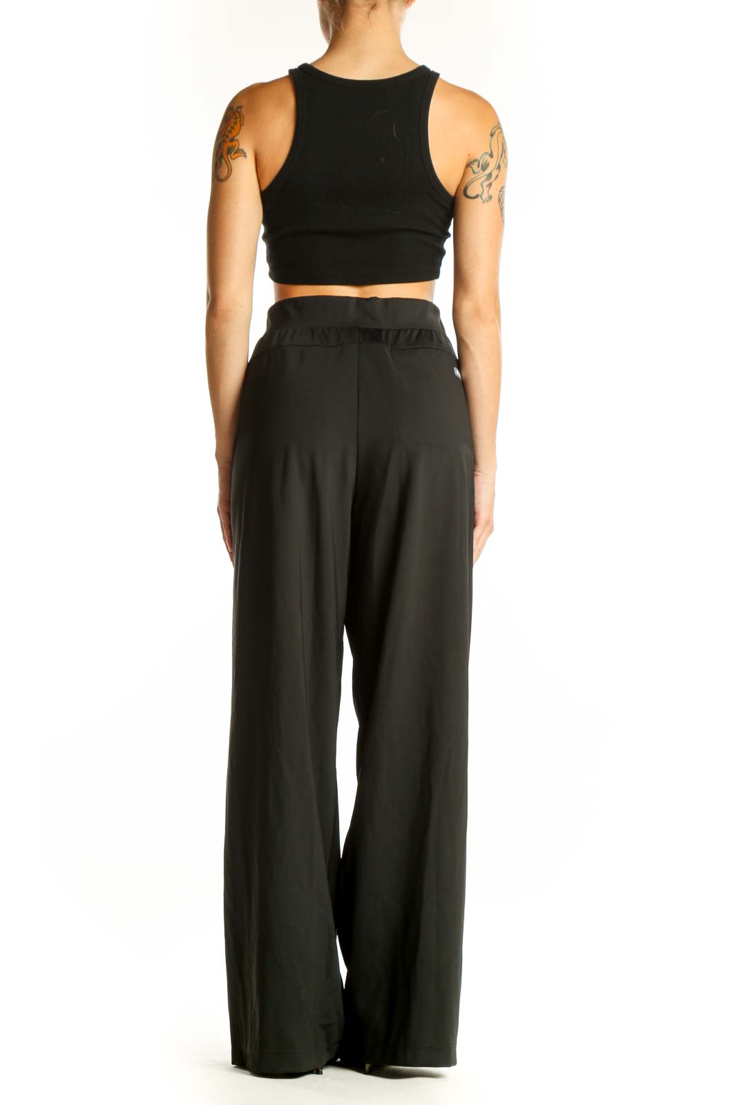 Side view of model wearing black wide-leg pants and crop top