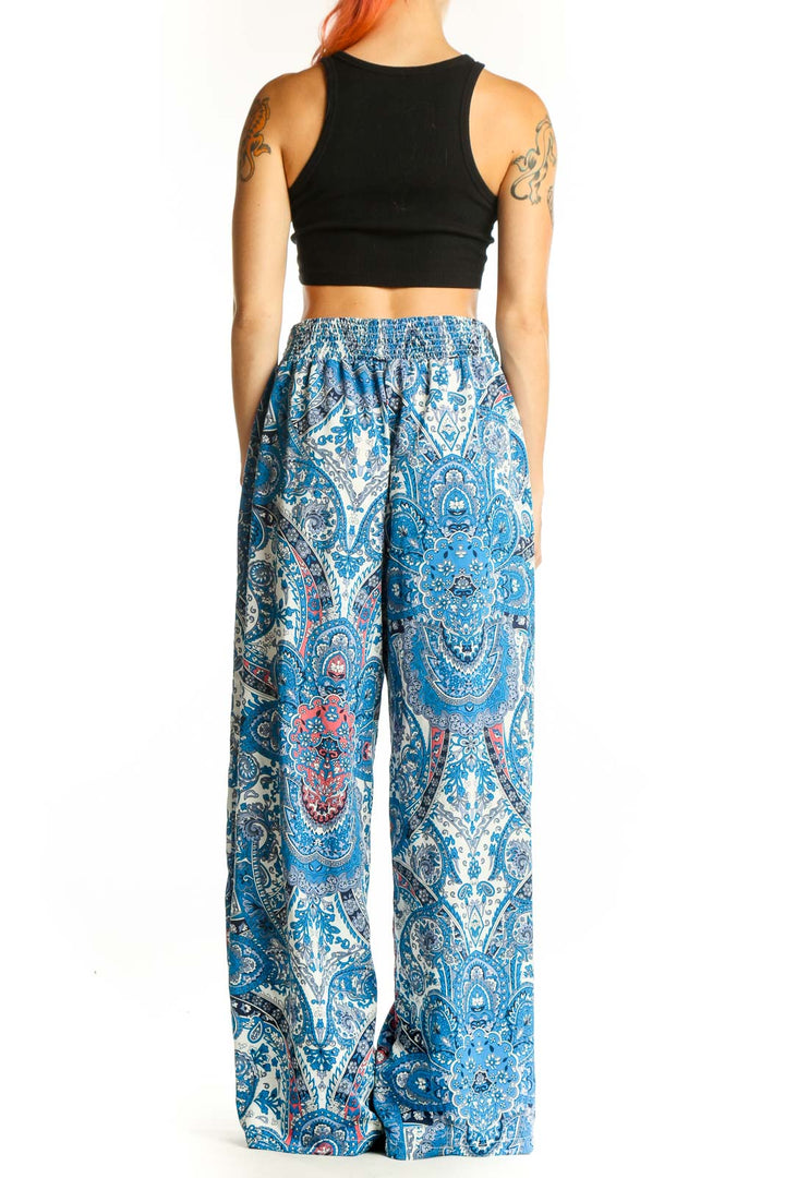 Side view of model wearing SilkRoll blue paisley wide-leg palazzo pants with black crop top