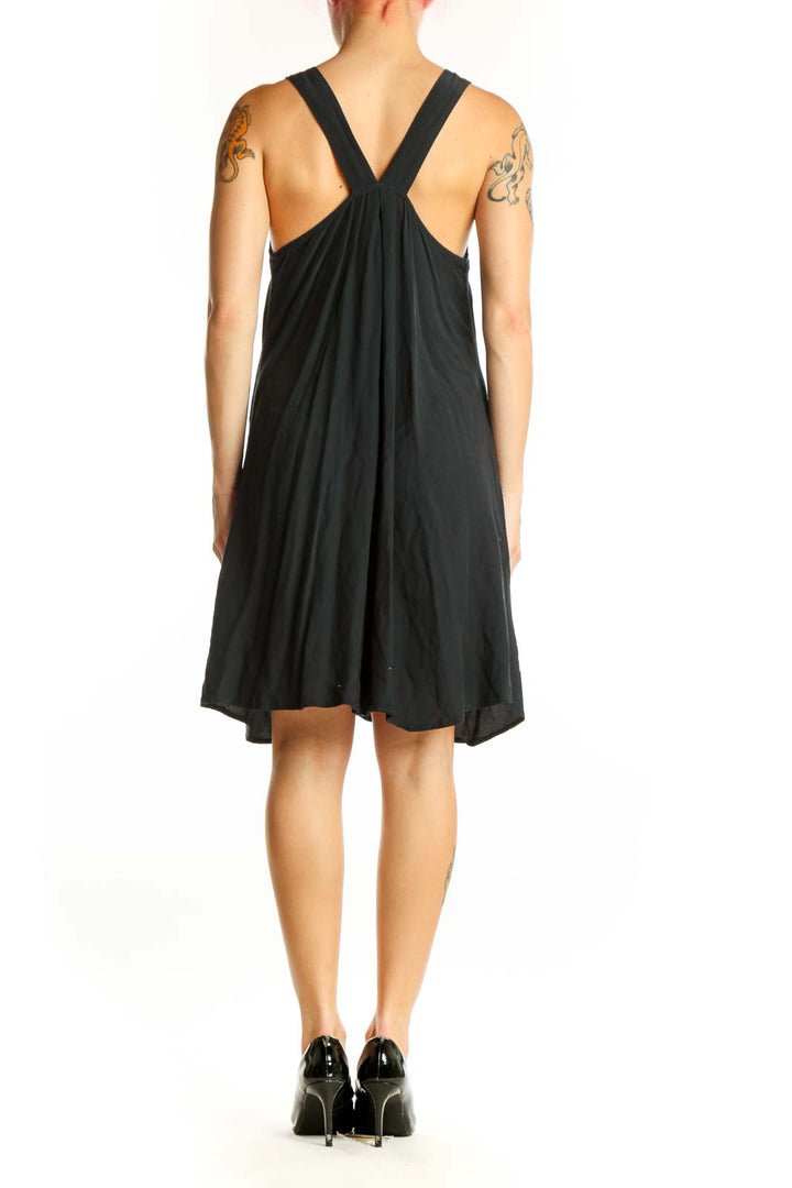 Black V-neck sleeveless dress with asymmetrical hemline, back view showing fluid drape