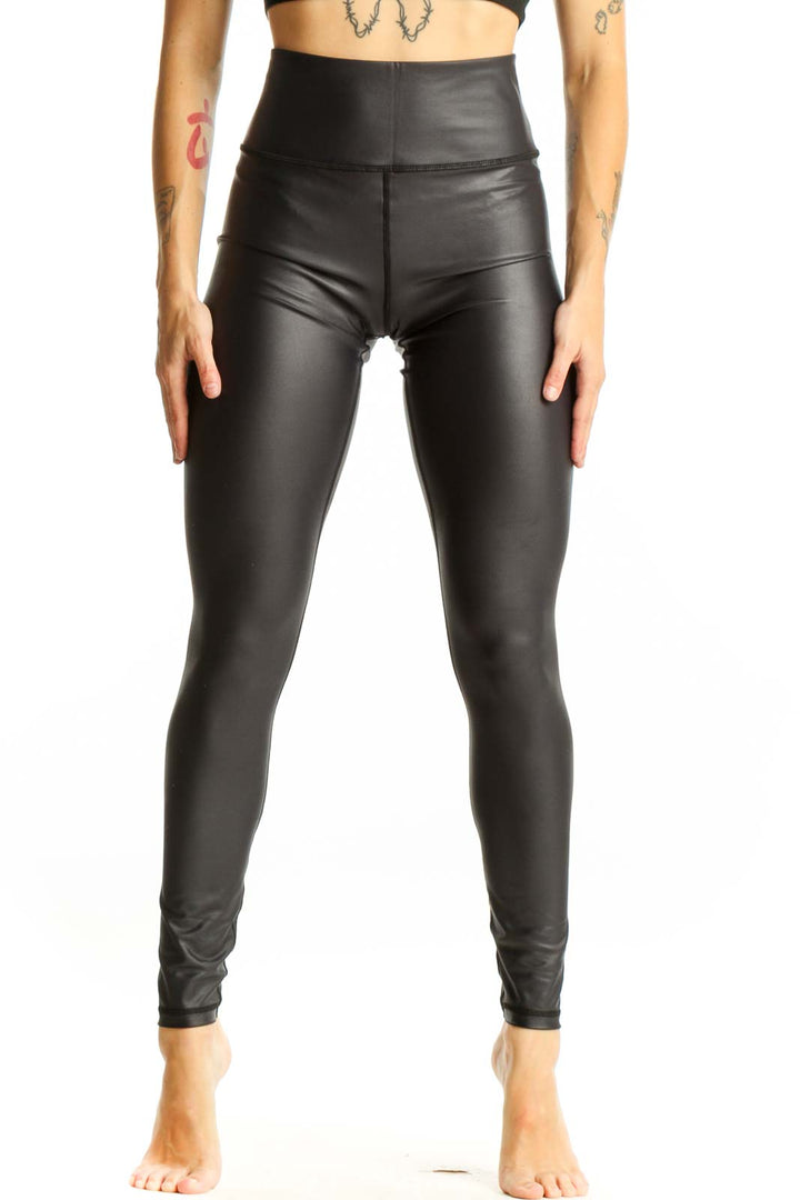 Front view of ZYIA black high-waisted faux leather leggings on model