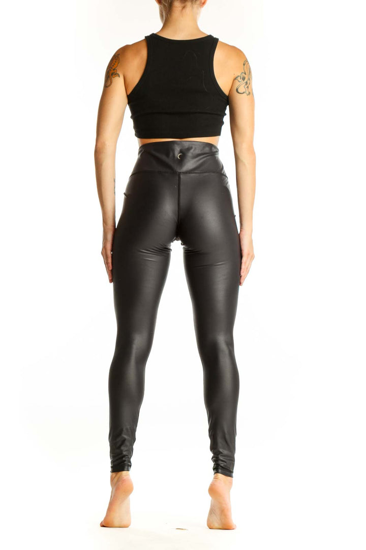 Side view of ZYIA black high-waisted faux leather leggings on model with black crop top