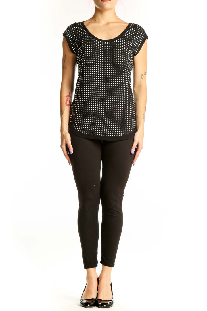 Black polka dot cap sleeve top with white dots, rounded neckline, and curved hem on model