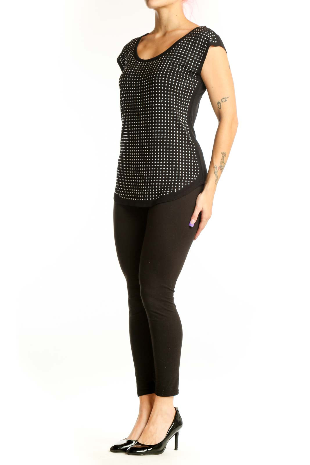 Black polka dot cap sleeve top with white dots, rounded neckline, and curved hem on model