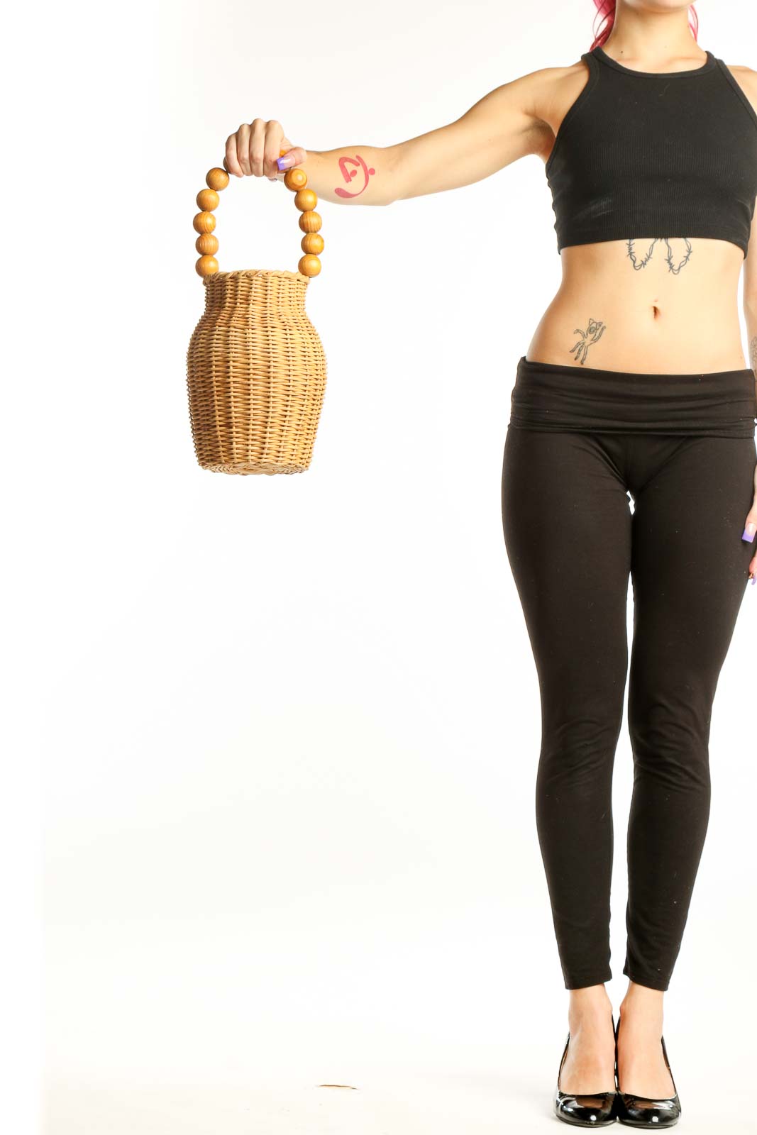 Natural wicker woven clutch with golden wooden bead handles held in hand, showing front view and textured weave detail