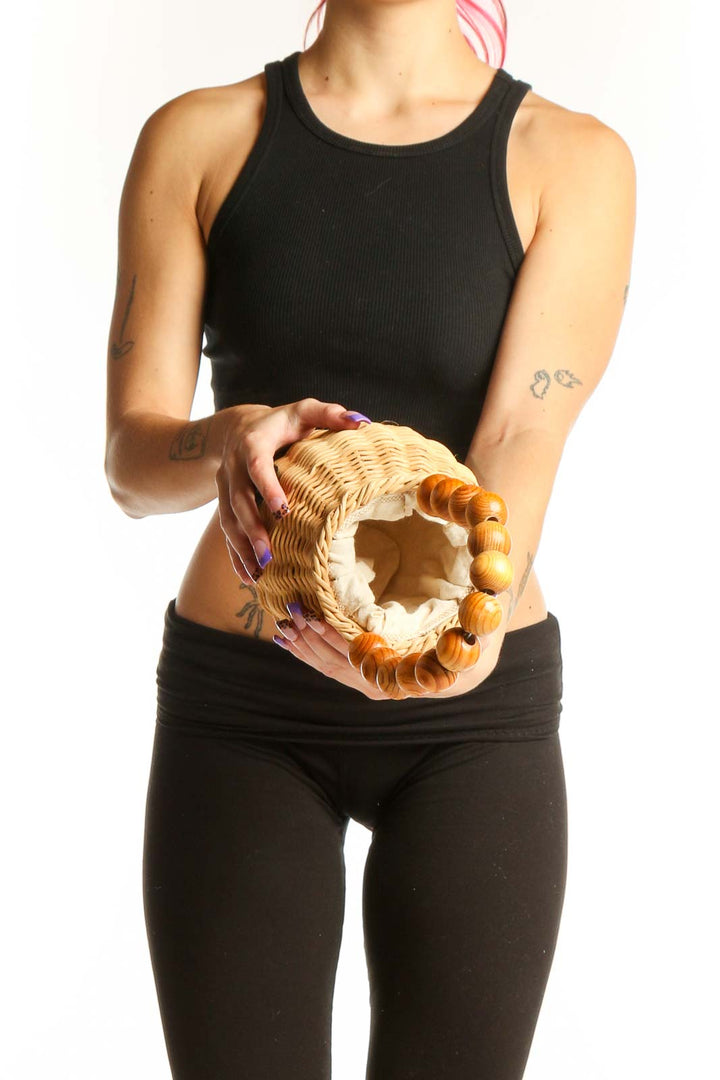 Back view of natural wicker clutch with wooden bead handles, displaying the handwoven texture and warm tan color