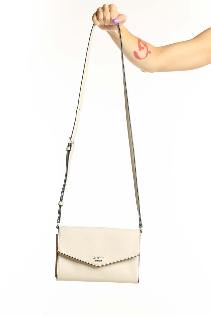 Cream Guess Crossbody Wallet Bag with adjustable strap and envelope flap design held in hand