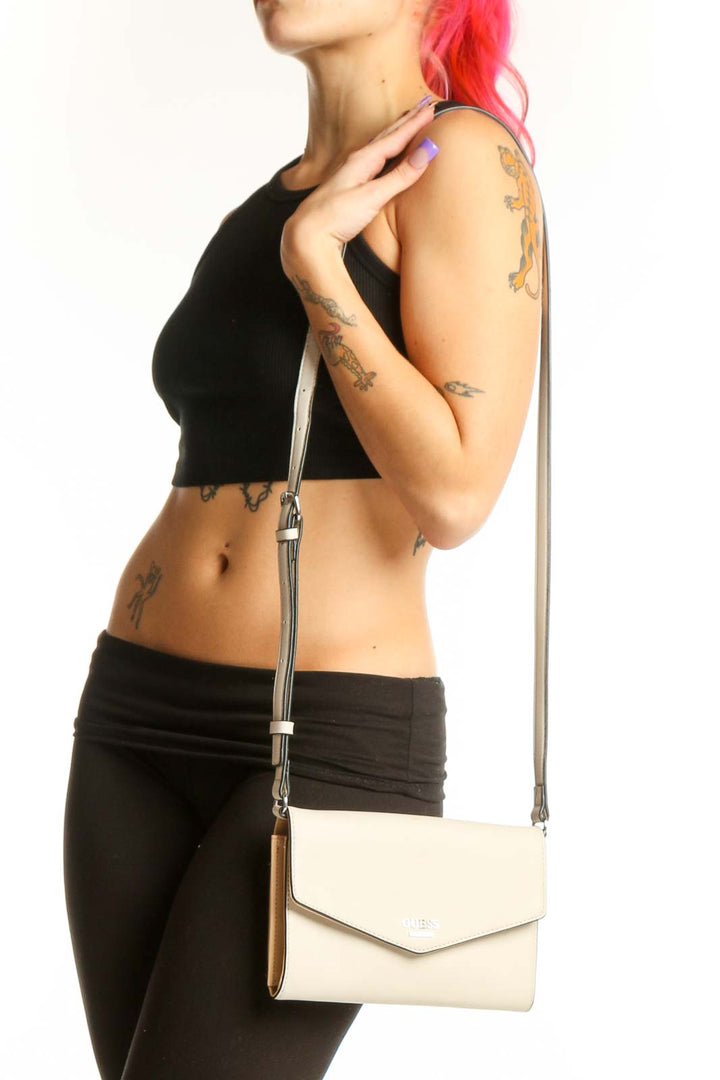 Cream Guess Crossbody Wallet Bag with adjustable strap and envelope flap design held in hand