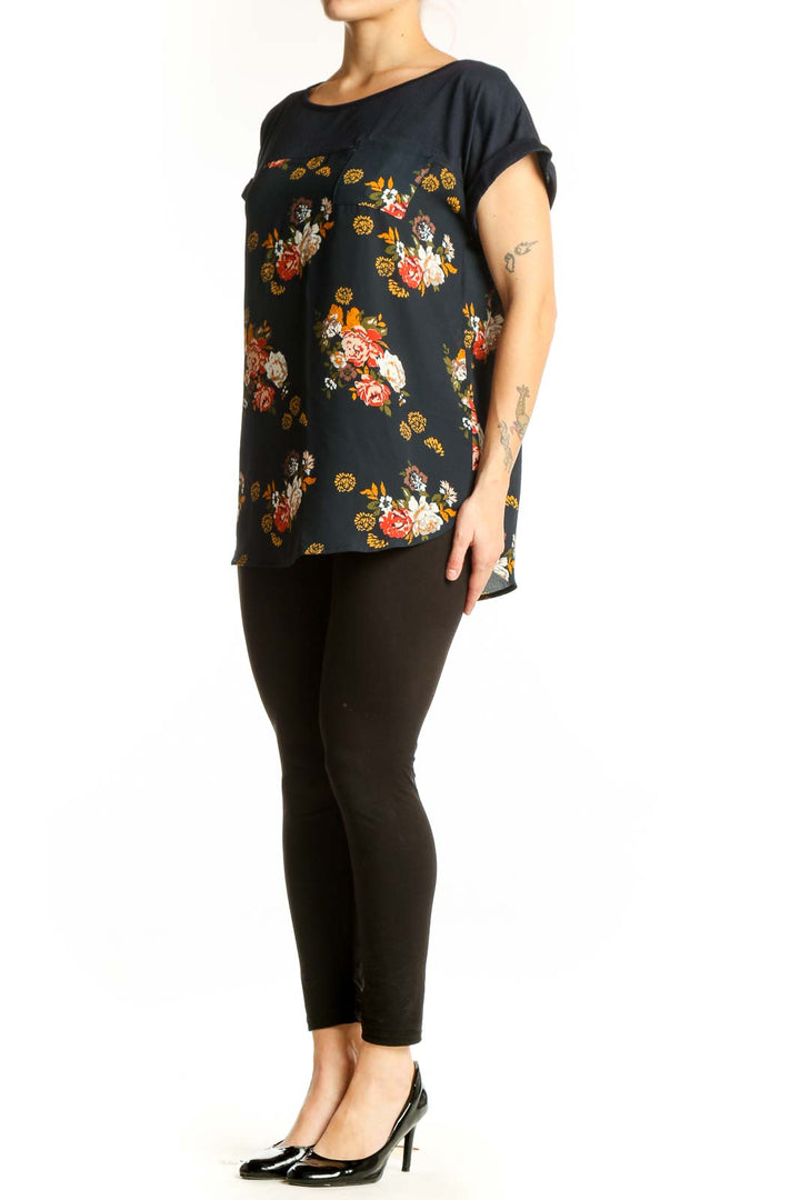Black floral print short sleeve top by Mason & Belle with red, orange, white, and golden yellow botanical flowers, relaxed fit