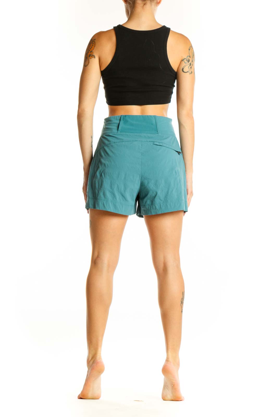 Side view of woman wearing teal Athleta athletic shorts with black crop top