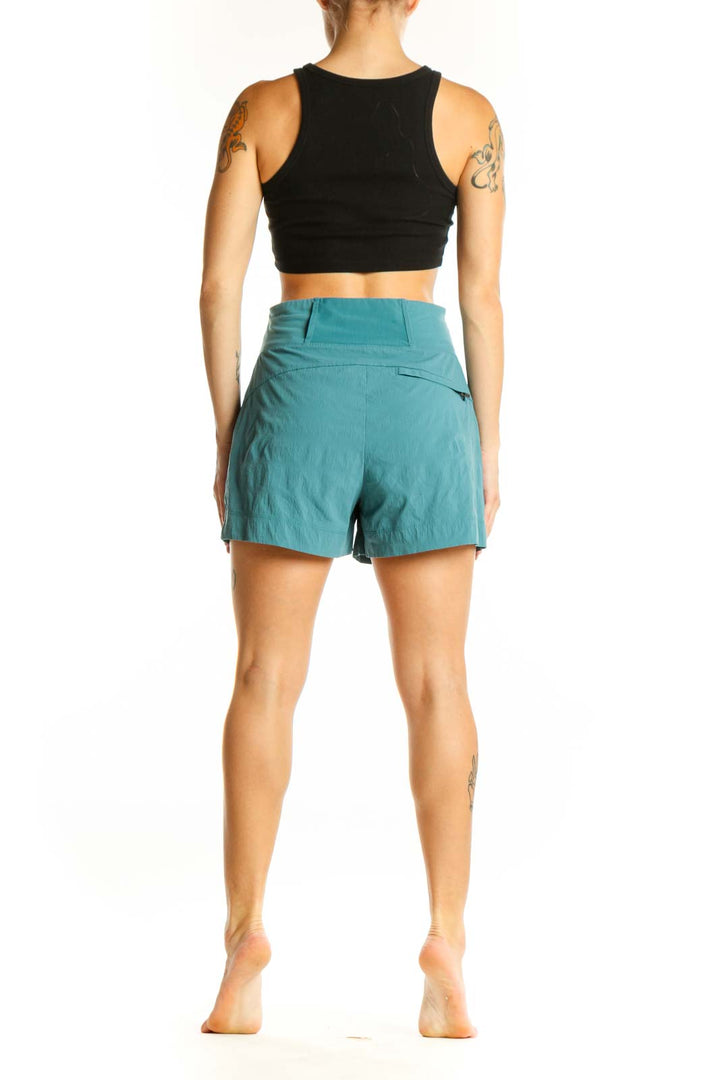 Side view of woman wearing teal Athleta athletic shorts with black crop top