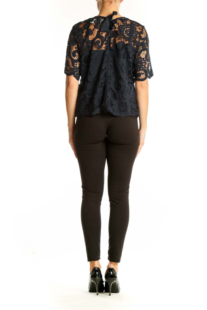 Side view of model wearing Nanette Lepore black lace top with black pants