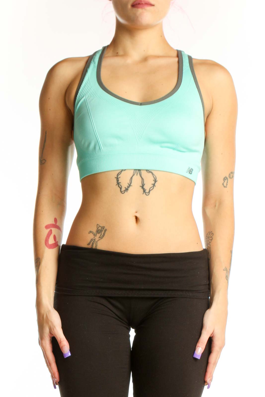 Mint green New Balance sports bra with charcoal trim, racerback design, front view on model