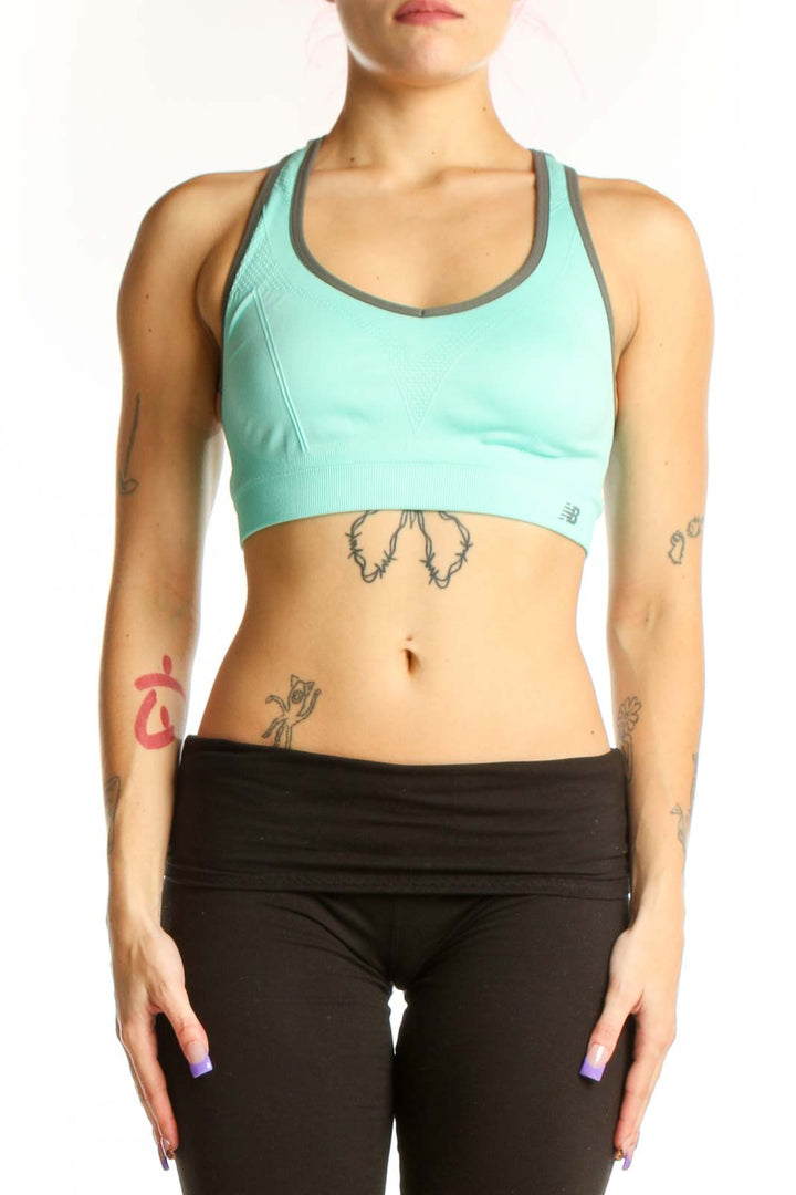 Mint green New Balance sports bra with charcoal trim, racerback design, front view on model