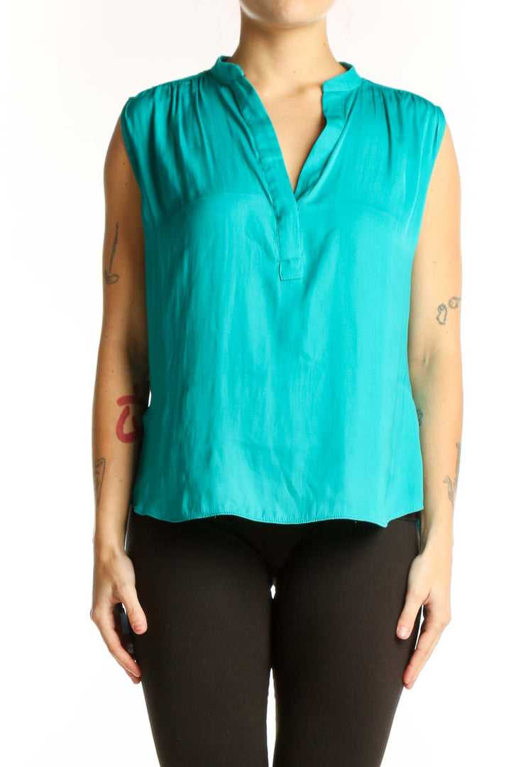 Turquoise sleeveless V-neck blouse with pleated shoulders, front view on model