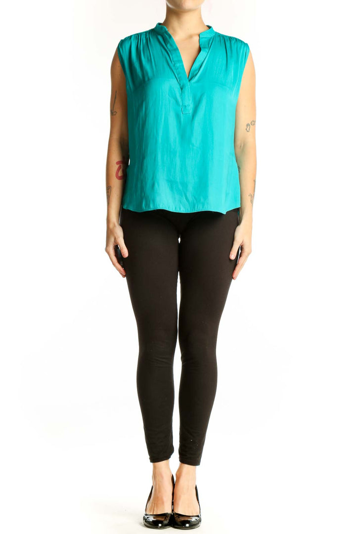 Turquoise sleeveless V-neck blouse with pleated shoulders, front view on model