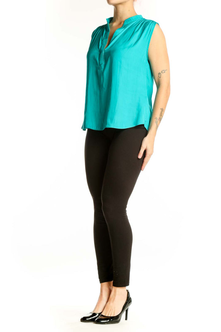 Turquoise sleeveless V-neck blouse with pleated shoulders, front view on model