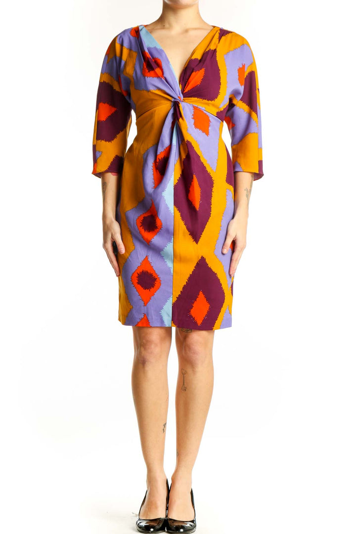 Front view of multicolor geometric print wrap dress with purple, orange, burgundy and gold diamond pattern by Vince Camuto