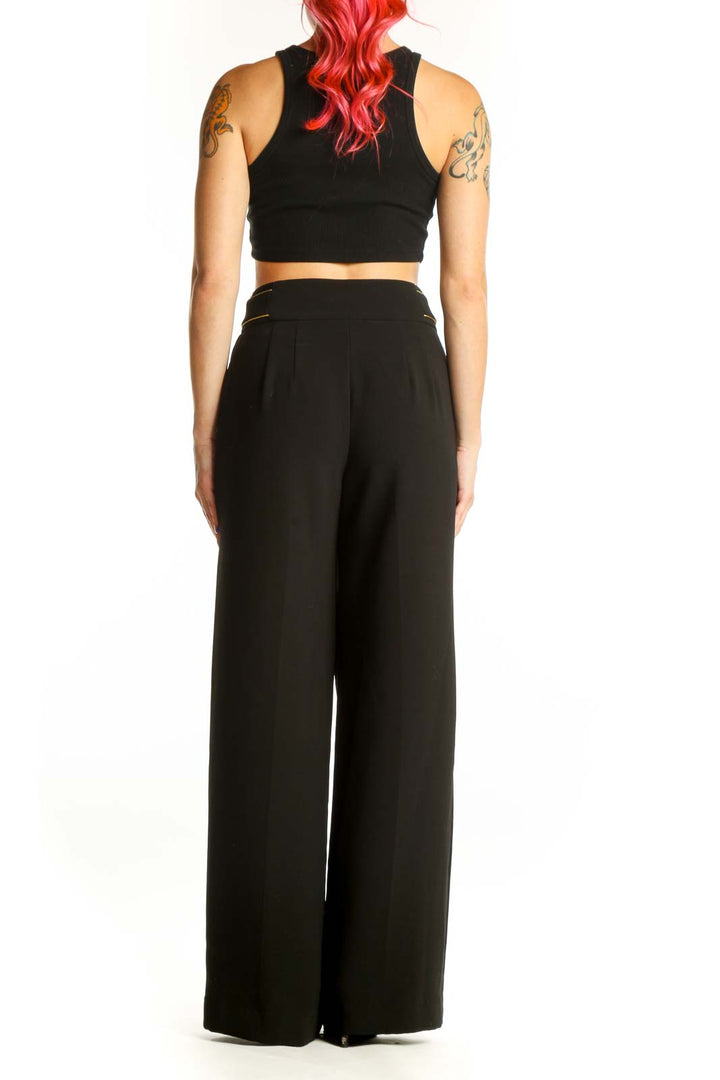 Black wide-leg pants with gold stud embellishment, back view showing flowing silhouette