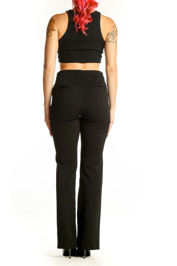 Black flare pants with button embellishments, back view showing elegant silhouette and leg details